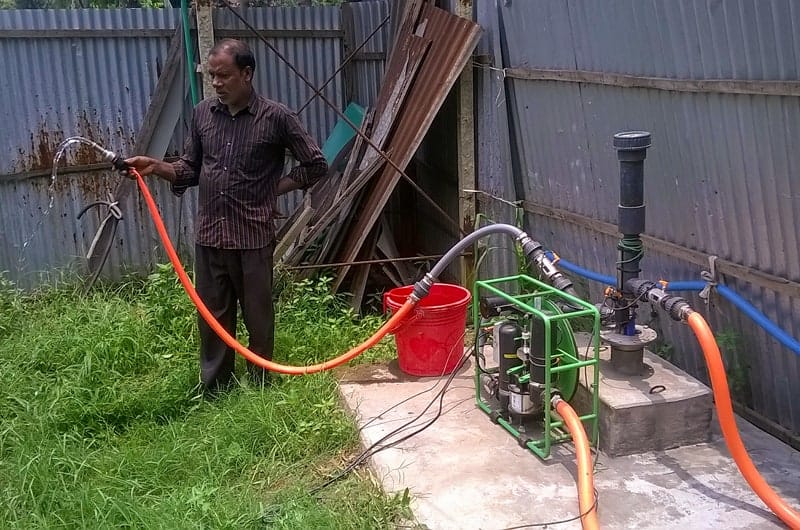 An Impact Pump field trial set up in Bangladesh with a farm worker spraying water.