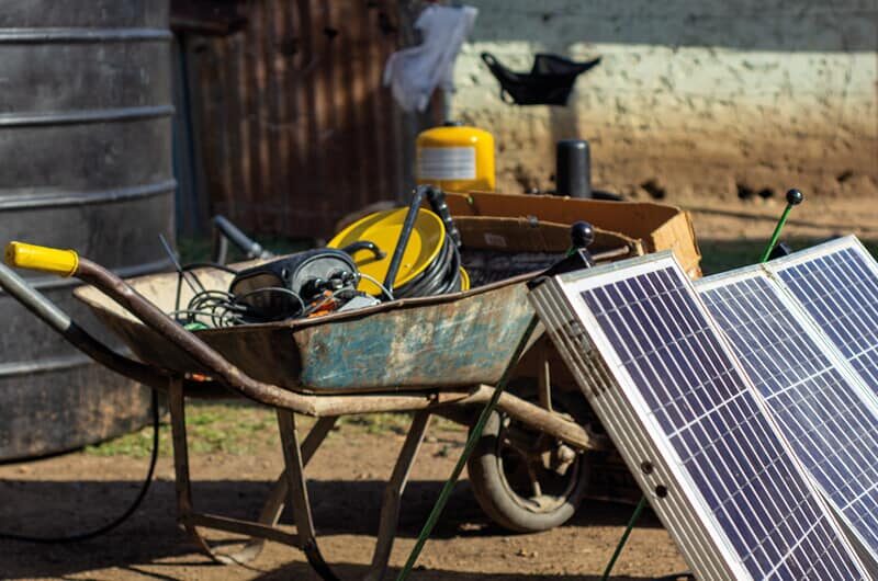 Wheelbarrow and solar panels near an Impact Pump installation