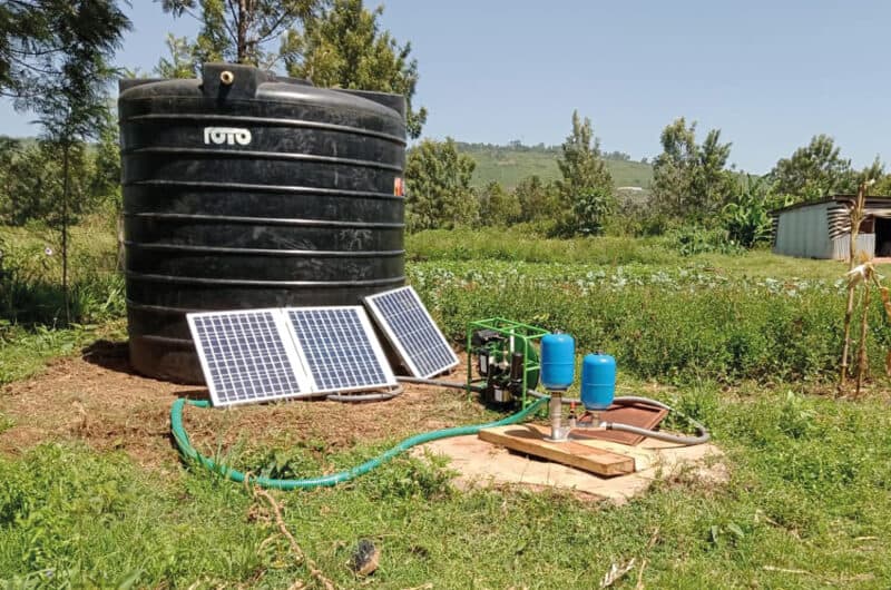 The Impact Pump, a submersible hydraulic ram pump, set up on a farm next to a tank and powered by the Futurepump SF2 a solar powered surface pump